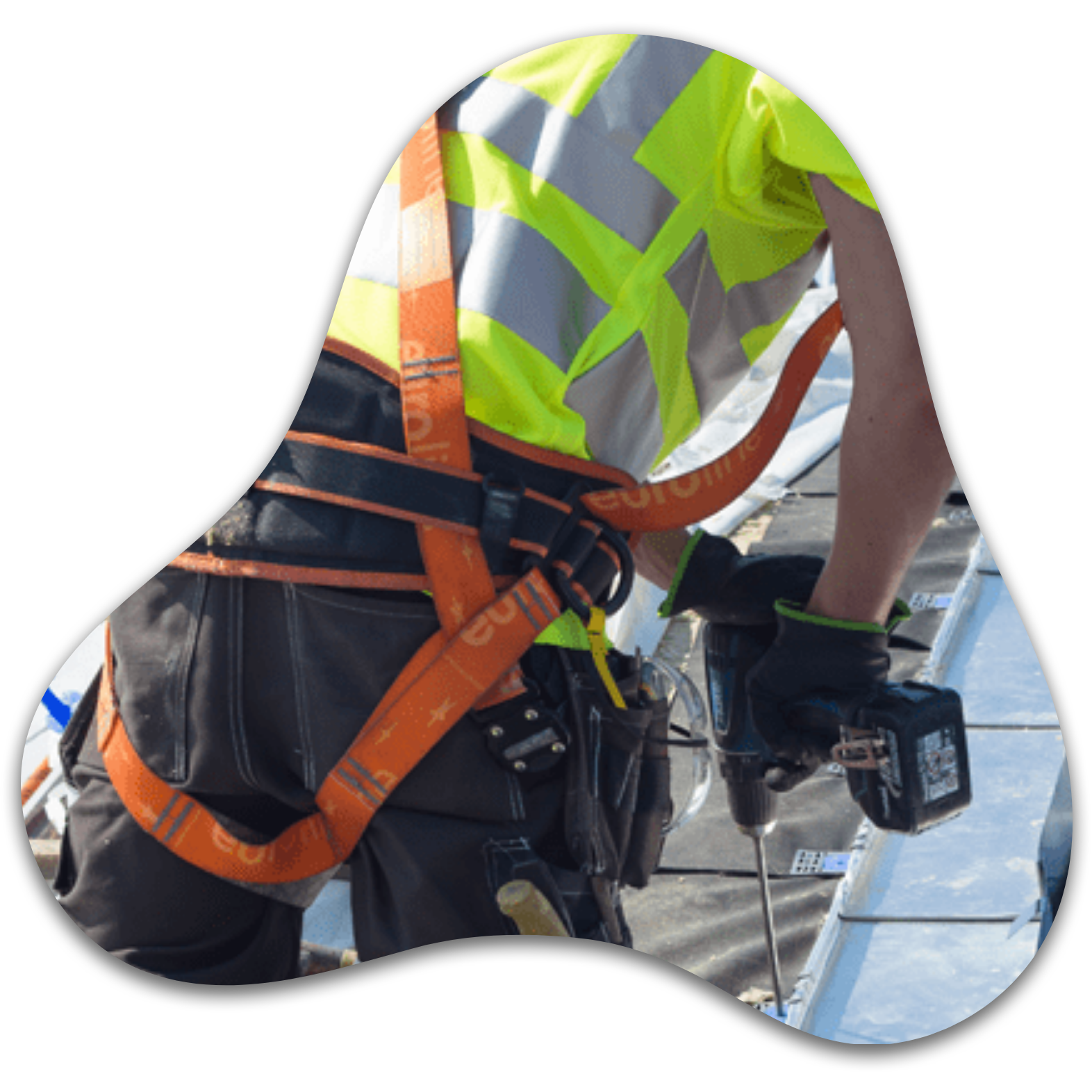 Worker installing sheet metal roofing with a drill and safety harness.
